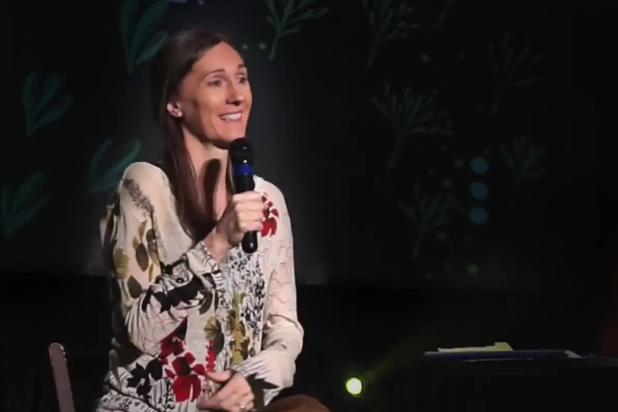 Kathy Steffan speaking on stage to a large audience