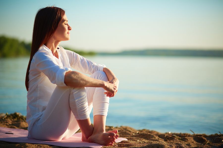 Person sitting quietly at the beach, looking relaxed and at ease.